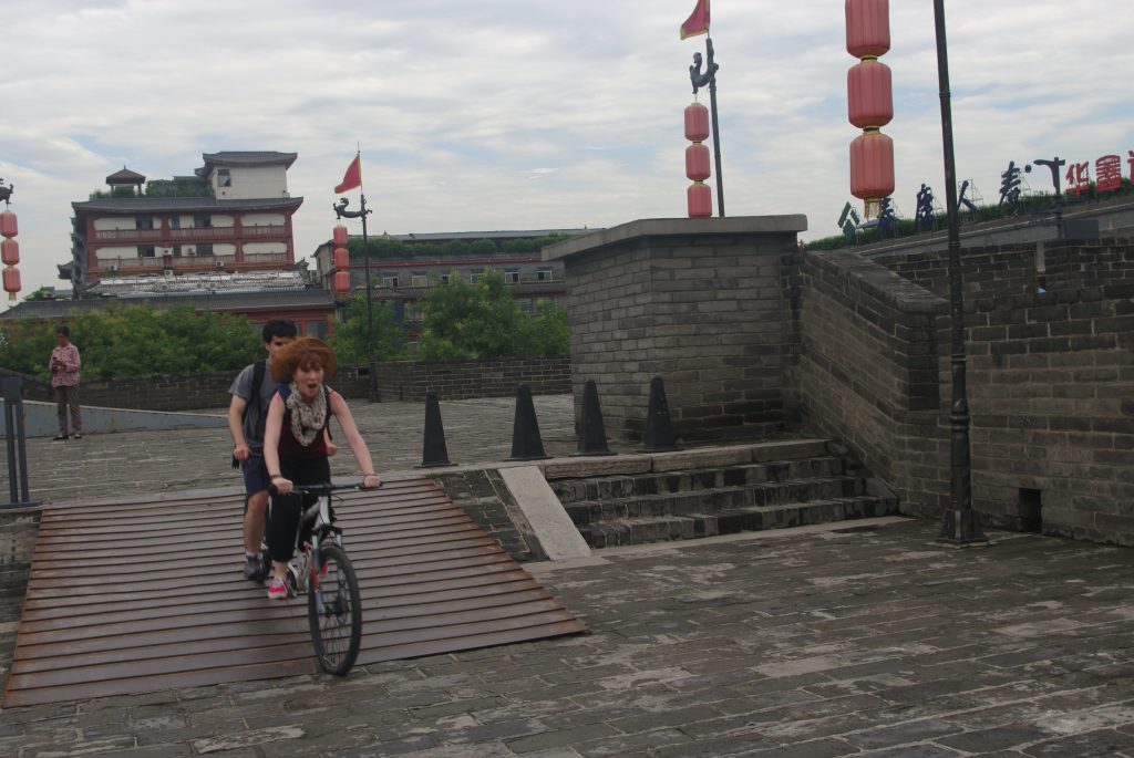 Alejandro and Samantha on a tandem cycling down a ramp on top of the Xi'an city wall